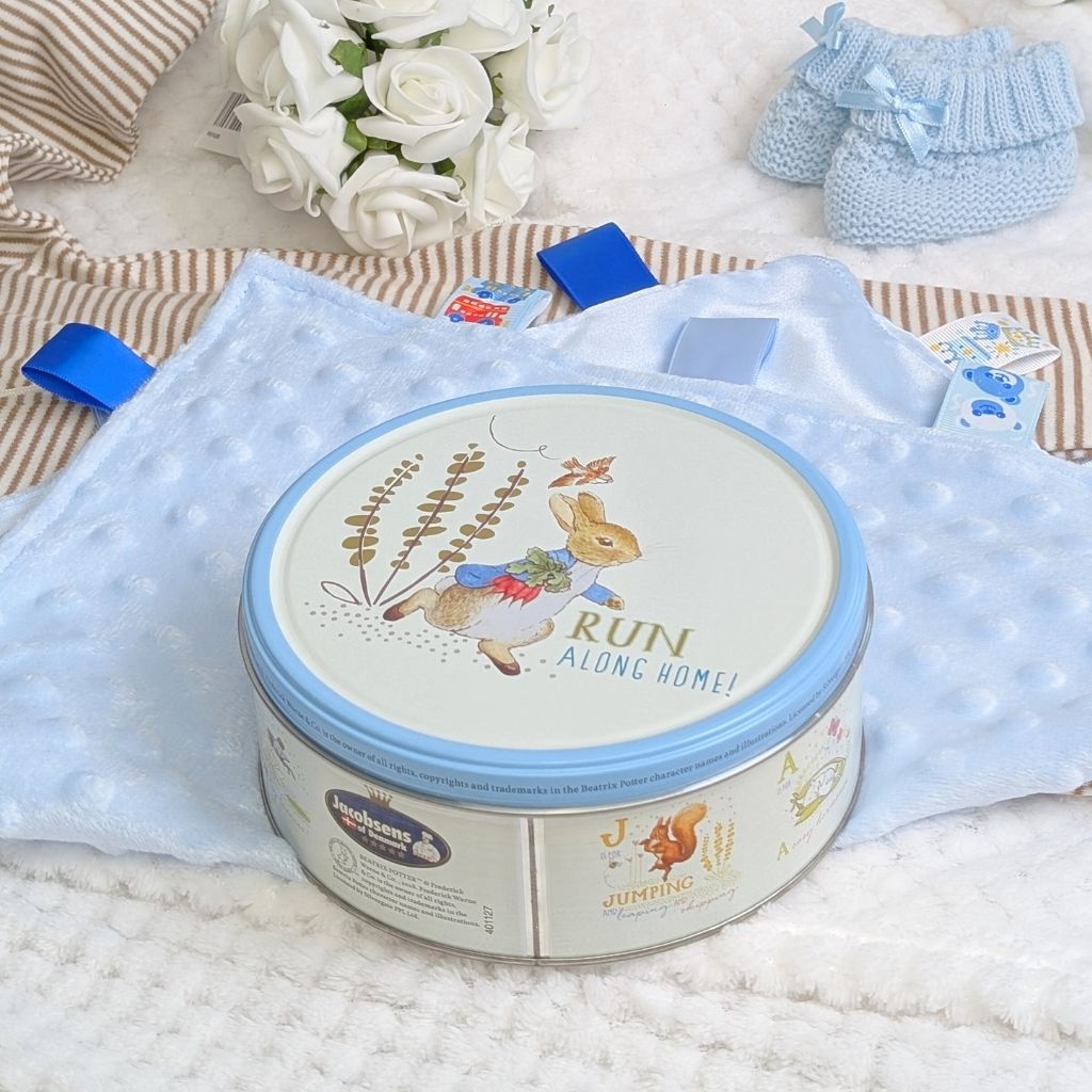 A biscuit tim featuring Peter Rabbit and the words Run Along Home on the lid. Fileld with delicous biscuits.