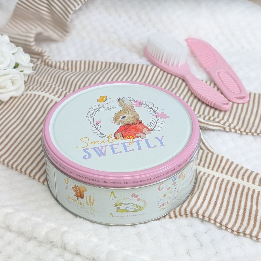 Peter rabbit biscuit tin with a pink edge filled with bisuits and which can also be used to keep babies keepsakes safe