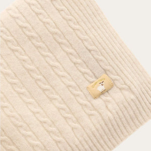 Beige oatmeal luxury knitted cashmere baby blanket with brand label.