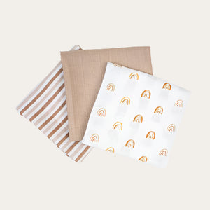 Three muslin cloths with beige patterns, including a striped pattern and rainbow design.
