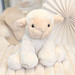 Plush eco friendly recycled lamb toy on a soft, beige blanket with a neutral background.