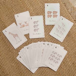 Number cards one to five spread on a woven surface beside a fanned stack of animal counting cards.