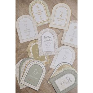 Floral milestone cards spread across a wooden surface with weeks and months visible