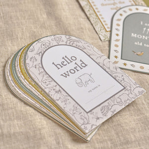 Stack of arched milestone cards topped by hello world on a wooden surface