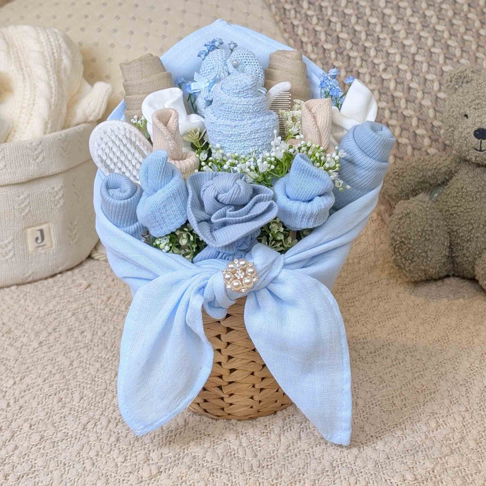 New baby boy gifts blue and beige baby clothing flower bouquet presented in a rattan plant pot by Bumbles and boo.