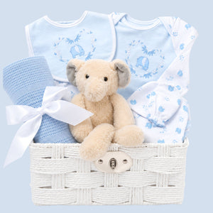 Baby boy gift basket with blue baby clothes, a teddy bear and a blanket.