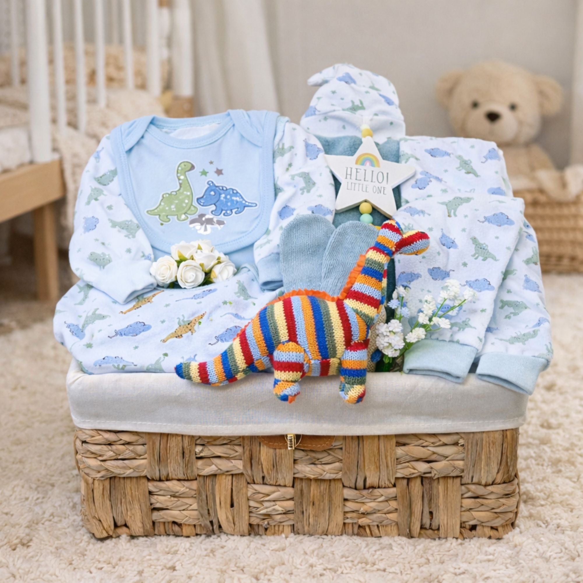 Present for a baby boy in a hamper with blue dinosaur clothing set.