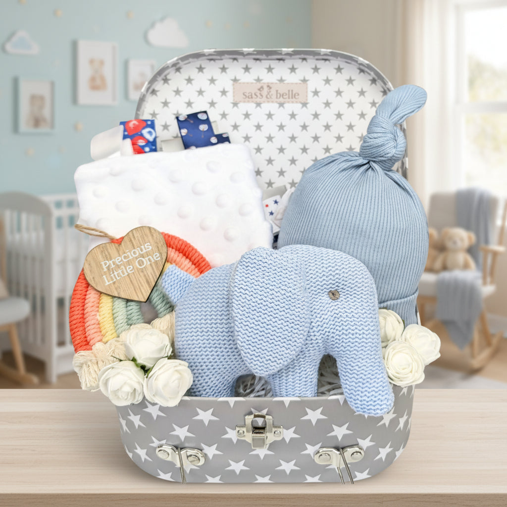 Baby boy gifts hamper with presents including blue elephant rattle and newborn hat. By Bumbles and Boo.