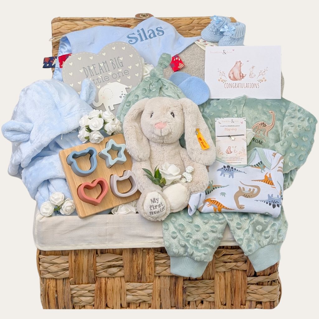 Large baby boy gifts hamper with cotton dinosaur clothing set and Steiff bunny in a hamper basket.