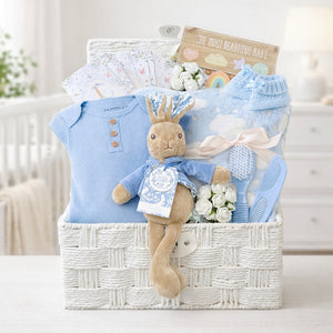 New baby boy gifts in a white hamper basket with peter rabbit, blue clothes and blanket