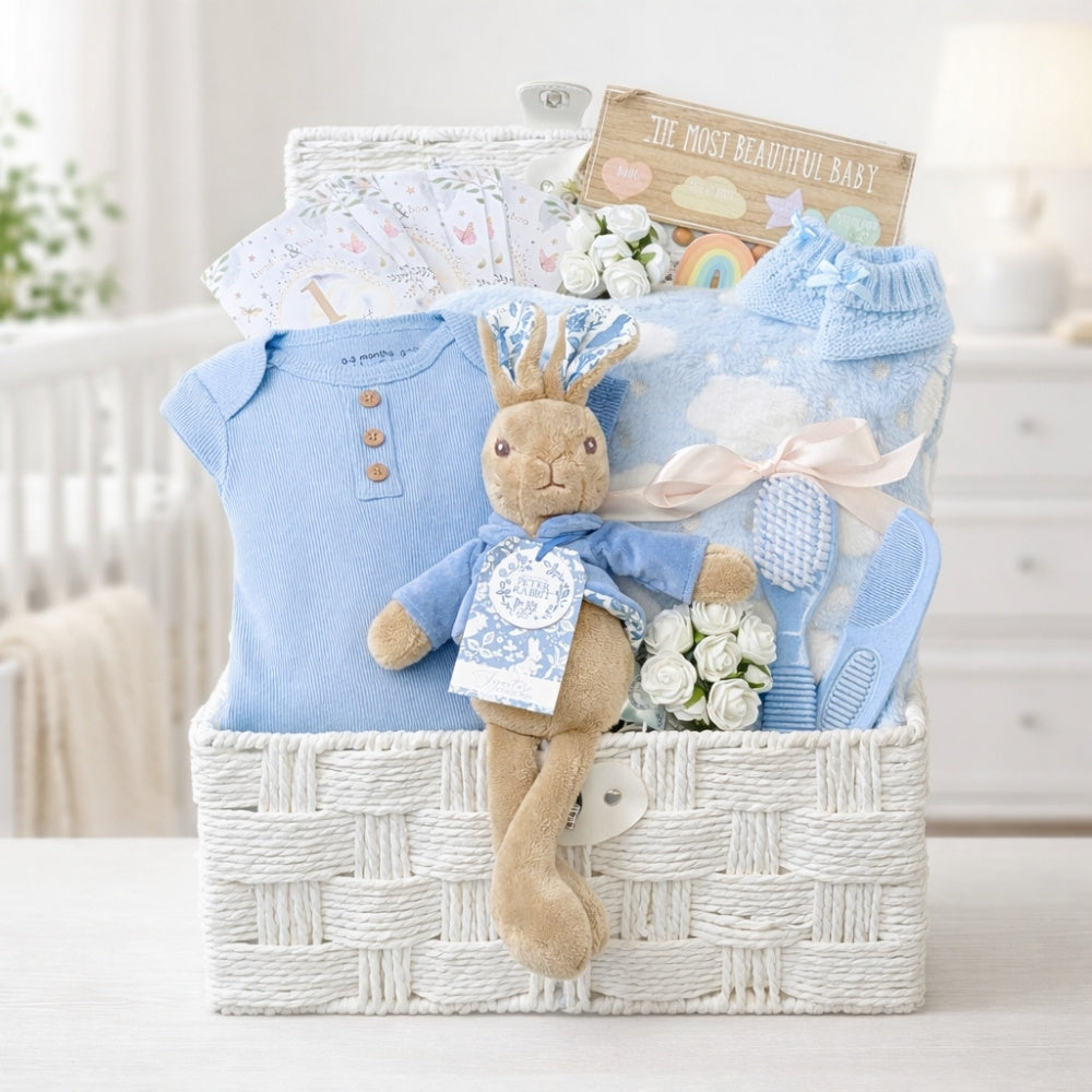 New baby boy gifts in a white hamper basket with peter rabbit, blue clothes and blanket