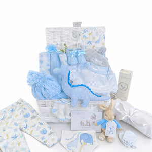 Baby boy gifts set with dinosaur clothing and organic skincare baby boy presents in a white basket.