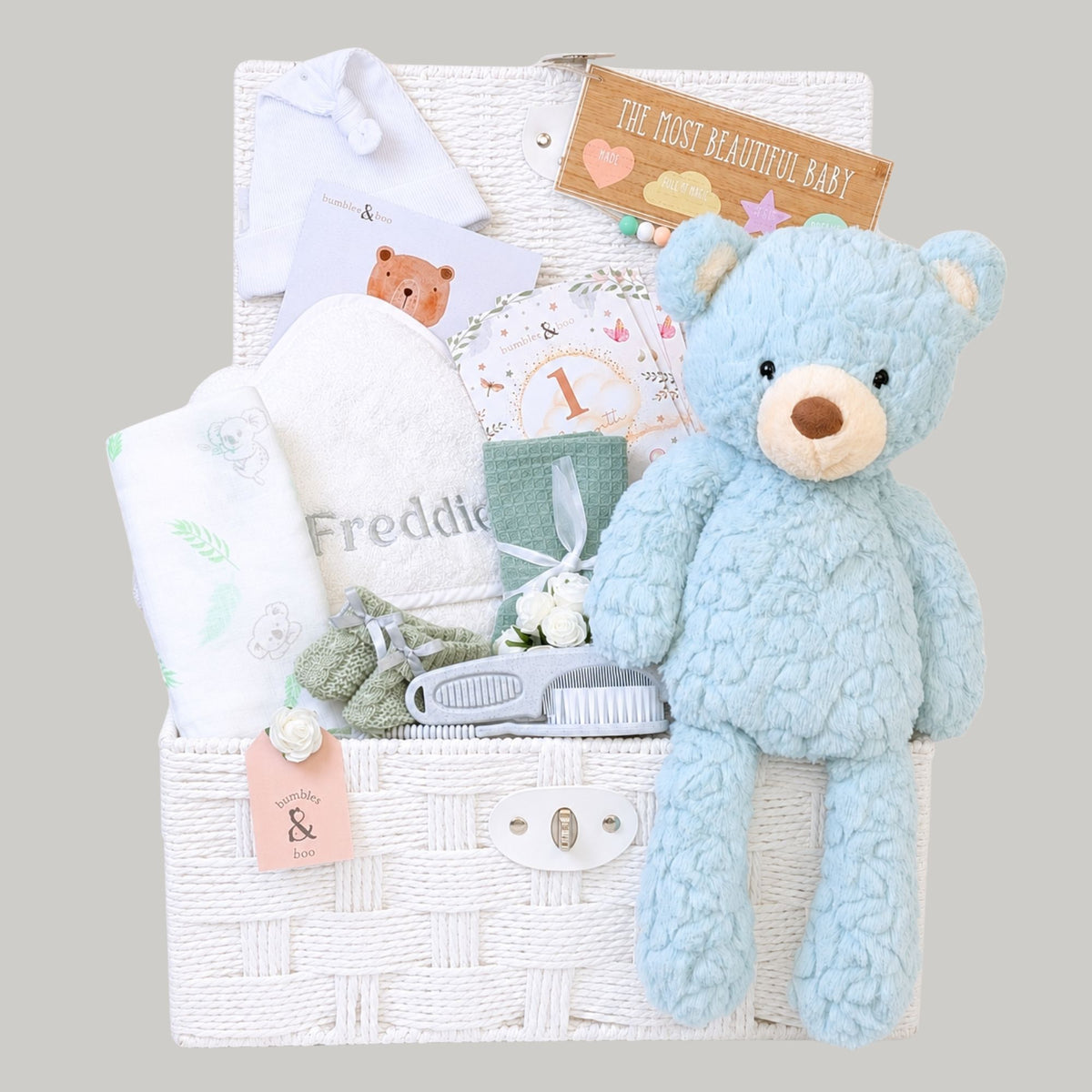 Baby gifts hamper basket with presents including blue teddy bear and personalised baby towel