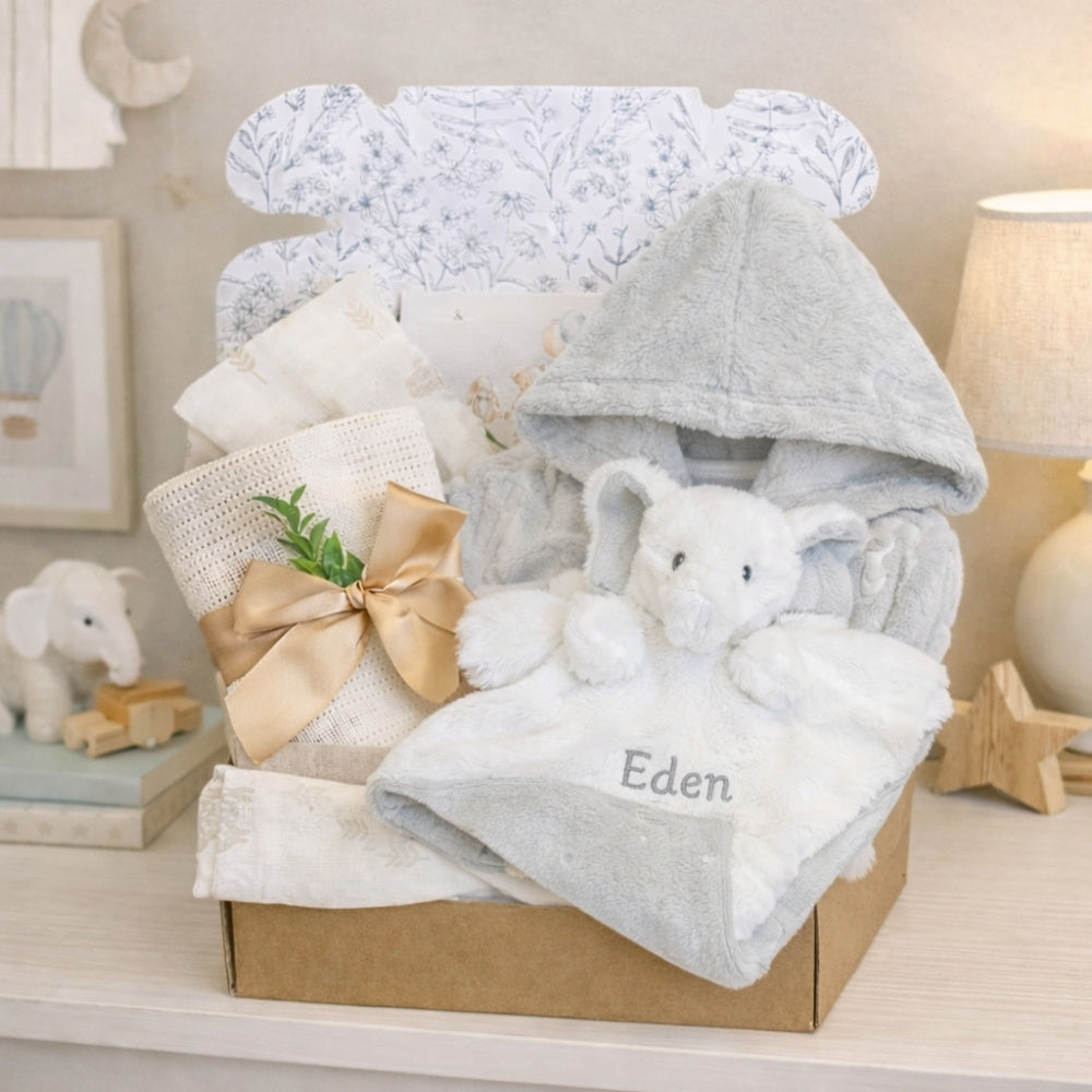 A baby gifts box with white and grey presents including elephant comforter and baby essentials