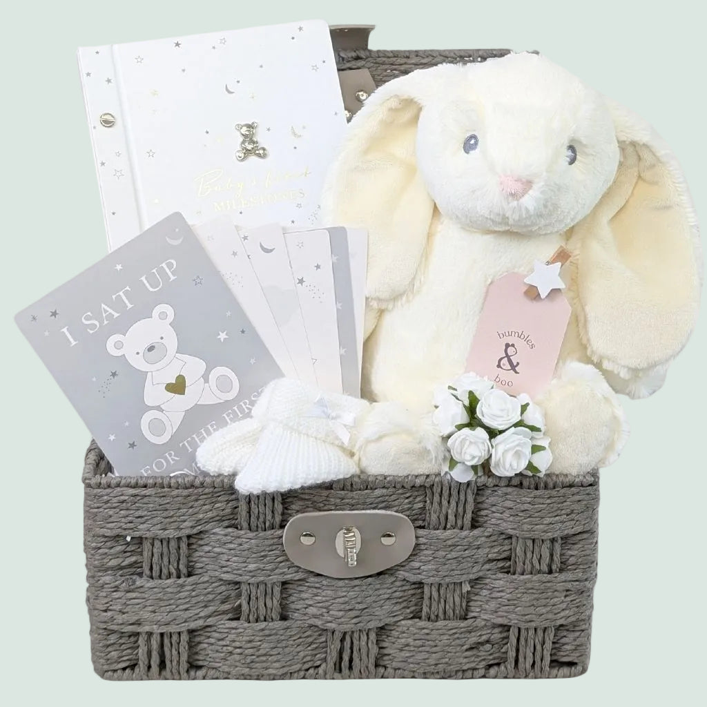 Baby gift hamper basket with white baby journal and milestone card set and large white bunny toy.