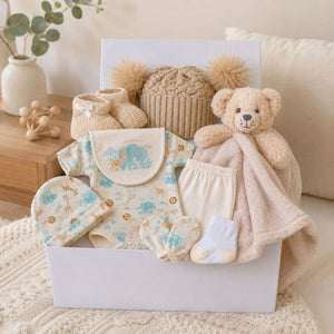 Baby gift hamper with presents including teddy bear, booties and green clothing packed in a gift box