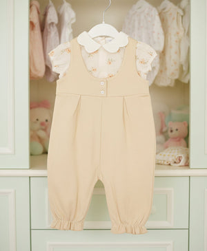 Baby girl beige cotton romper outfit with floral print short sleeve top and long romper, displayed on hanger in nursery.