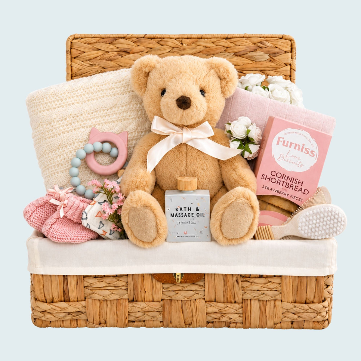 New baby girl gifts in a hamper basket with presents including a teddy bear and biscuits for the new parents.