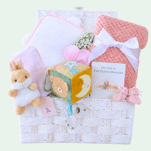 Baby girl hamper gift with pink congratulations gifts in a bear and bunny theme in a white gift basket.