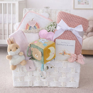 Baby girl gifts hamper with congratulations presents with a bear and bunny theme in a white gift basket.