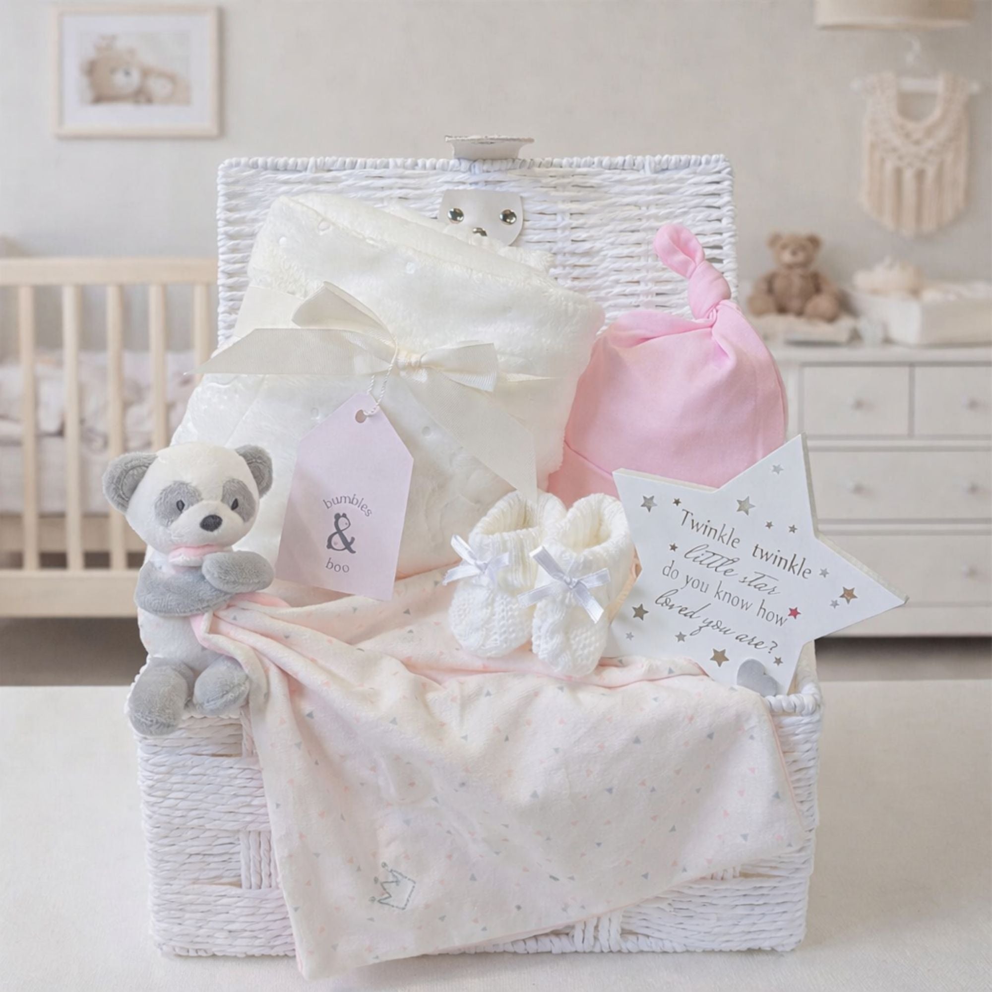 Luxury baby girl gifts set with in a white hamper basket with a bear comforter and soft white blanket.