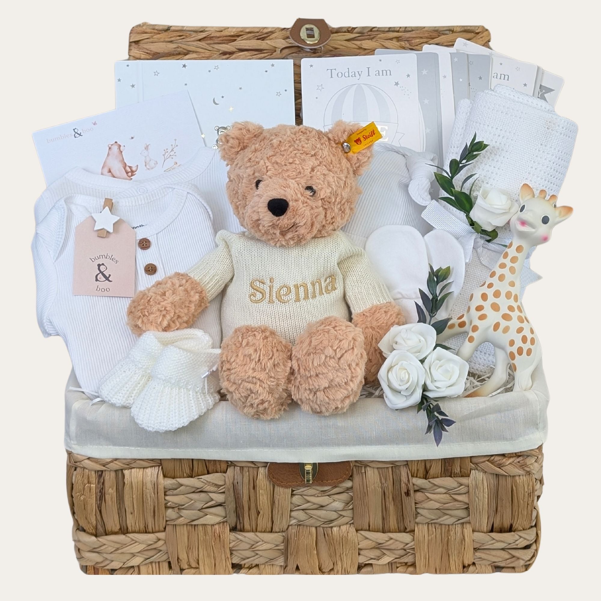A gifts hamper for a new baby in a seagrass basket with a teddy, baby clothing and other presents. Can be personalised. Bumbles and Boo.