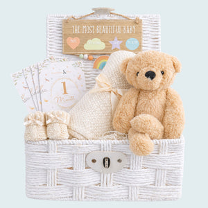 New baby hamper with a teddy bear and blanket in a white basket.