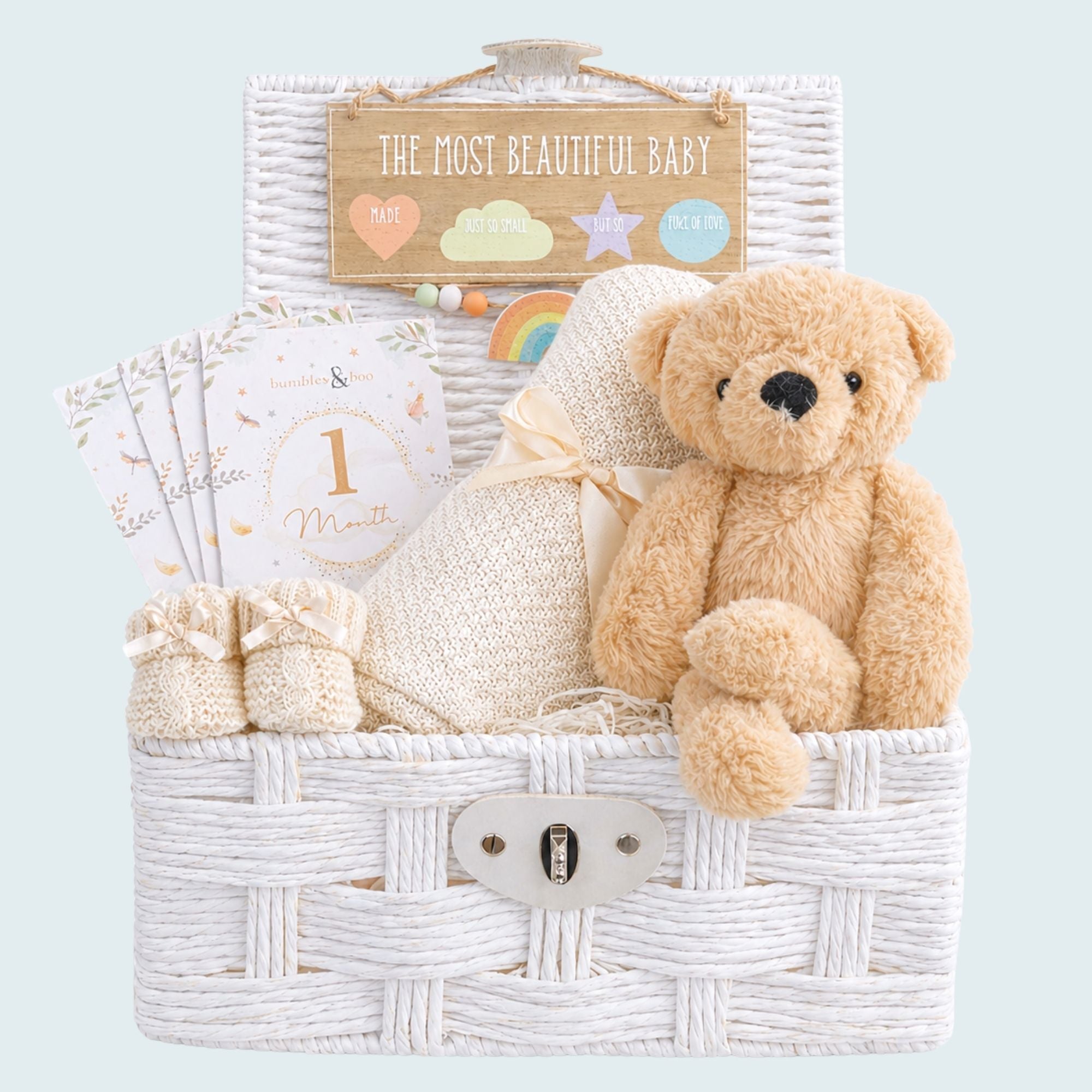 New baby hamper with a teddy bear and blanket in a white basket.