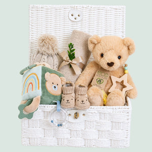 Newborn baby gifts hamper with teddy bear and soft blanket in a white basket