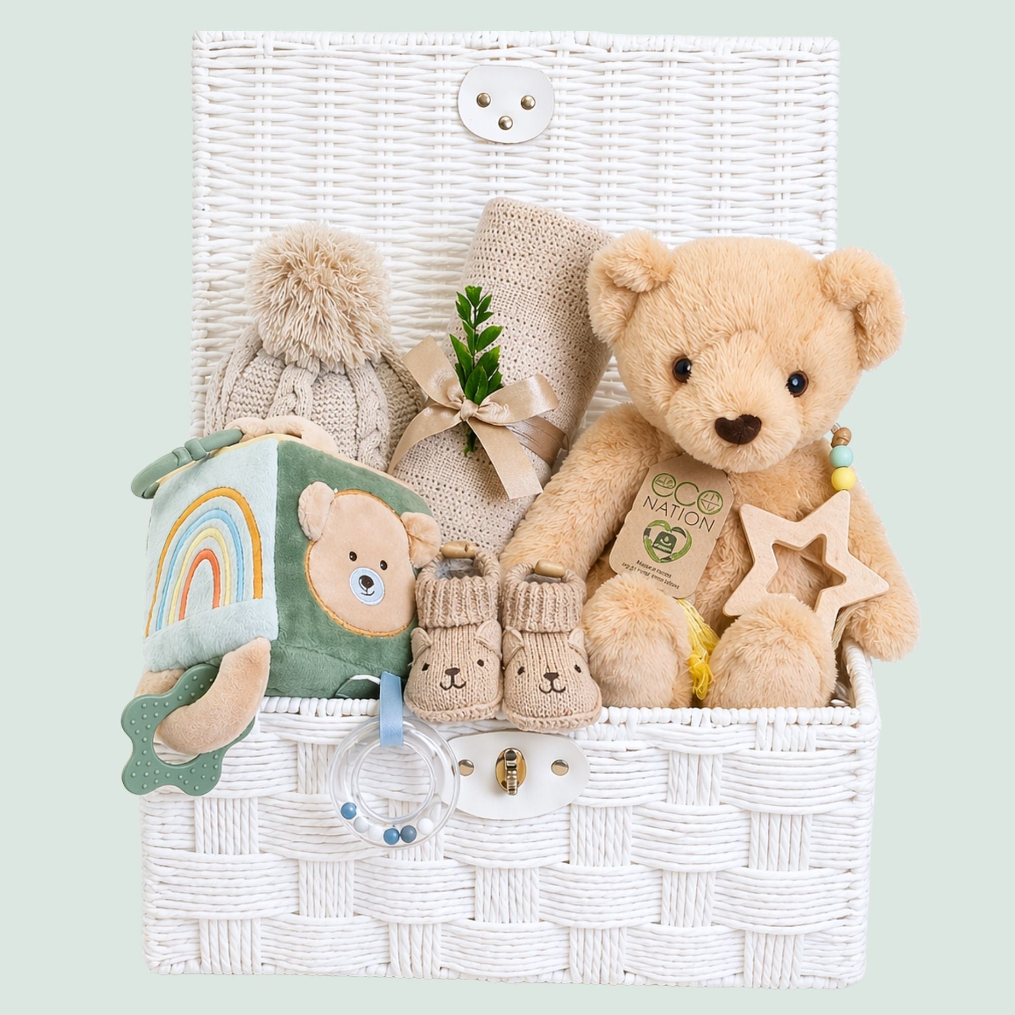 Baby gifts in a hamper with beige blanket and hat and teddy bear soft toy.