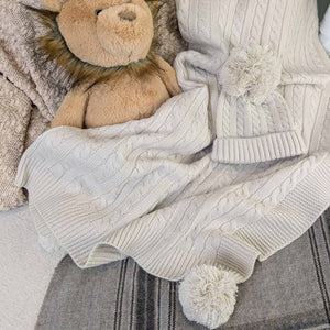 knit baby blanket with pompoms and matching knit hat