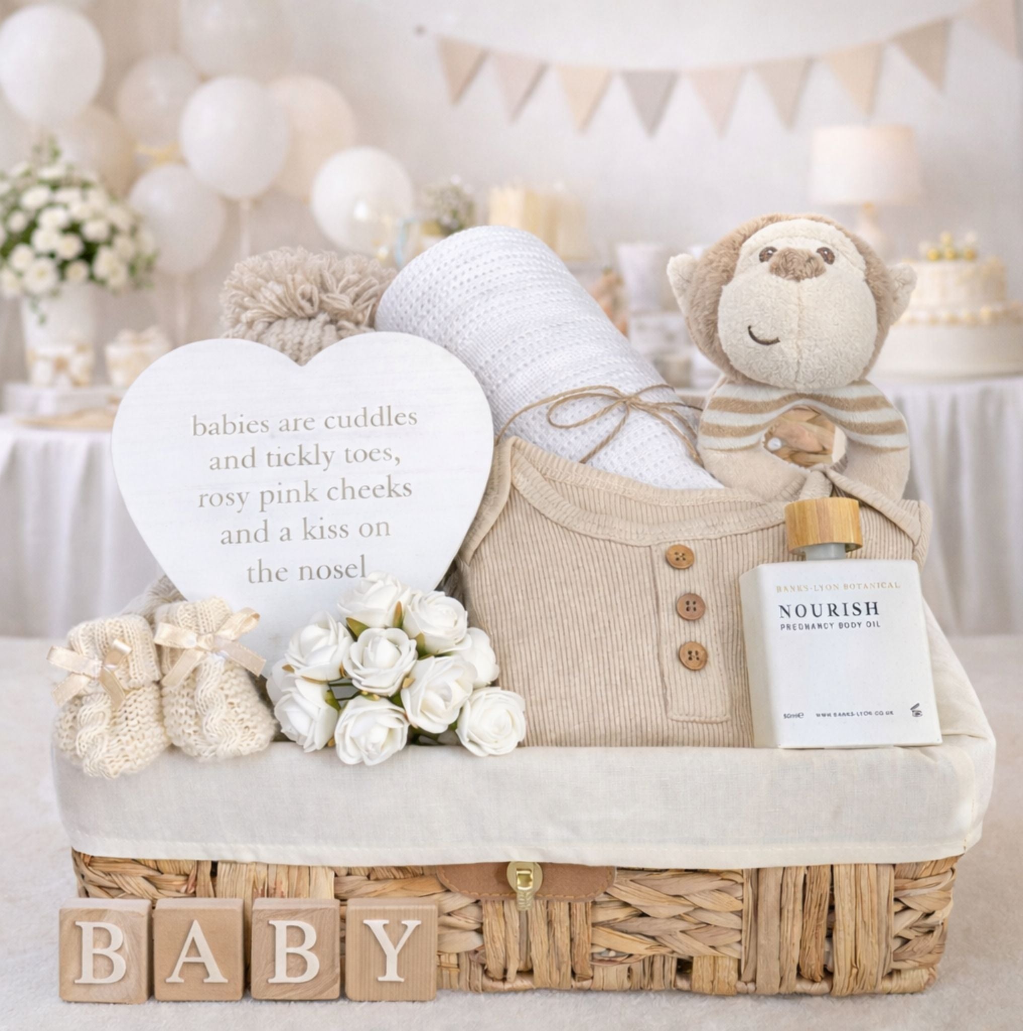 A baby shower bundle of presents to include monkey soft toy and clothing in a hamper basket.