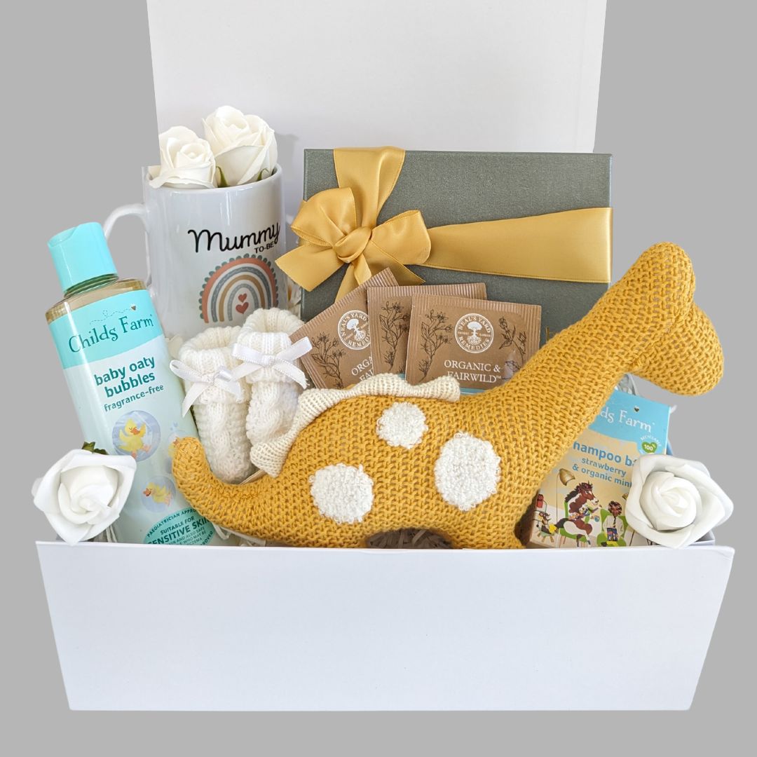 Baby shower gifts box with yellow dinosaur toy, baby bubbles, and mummy mug. 