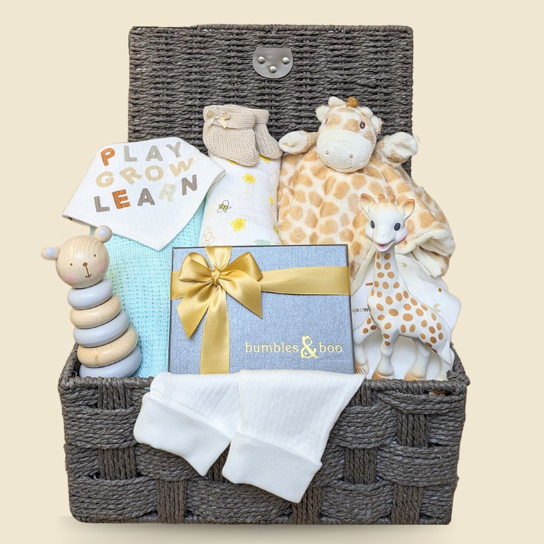 Baby shower hamper gifts with giraffe theme and organic clothing. Presents are packed in a brown basket.