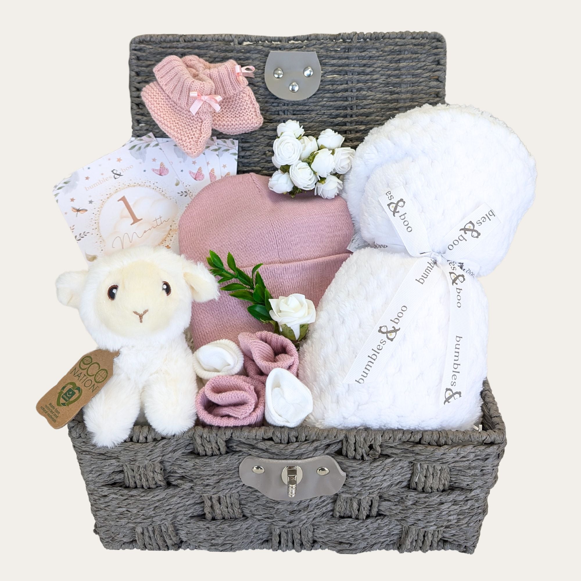 Baby shower gifts basket with pink baby clothes, lamb soft toy and white blanket packed in a wicker hamper by Bumbles & Boo.
