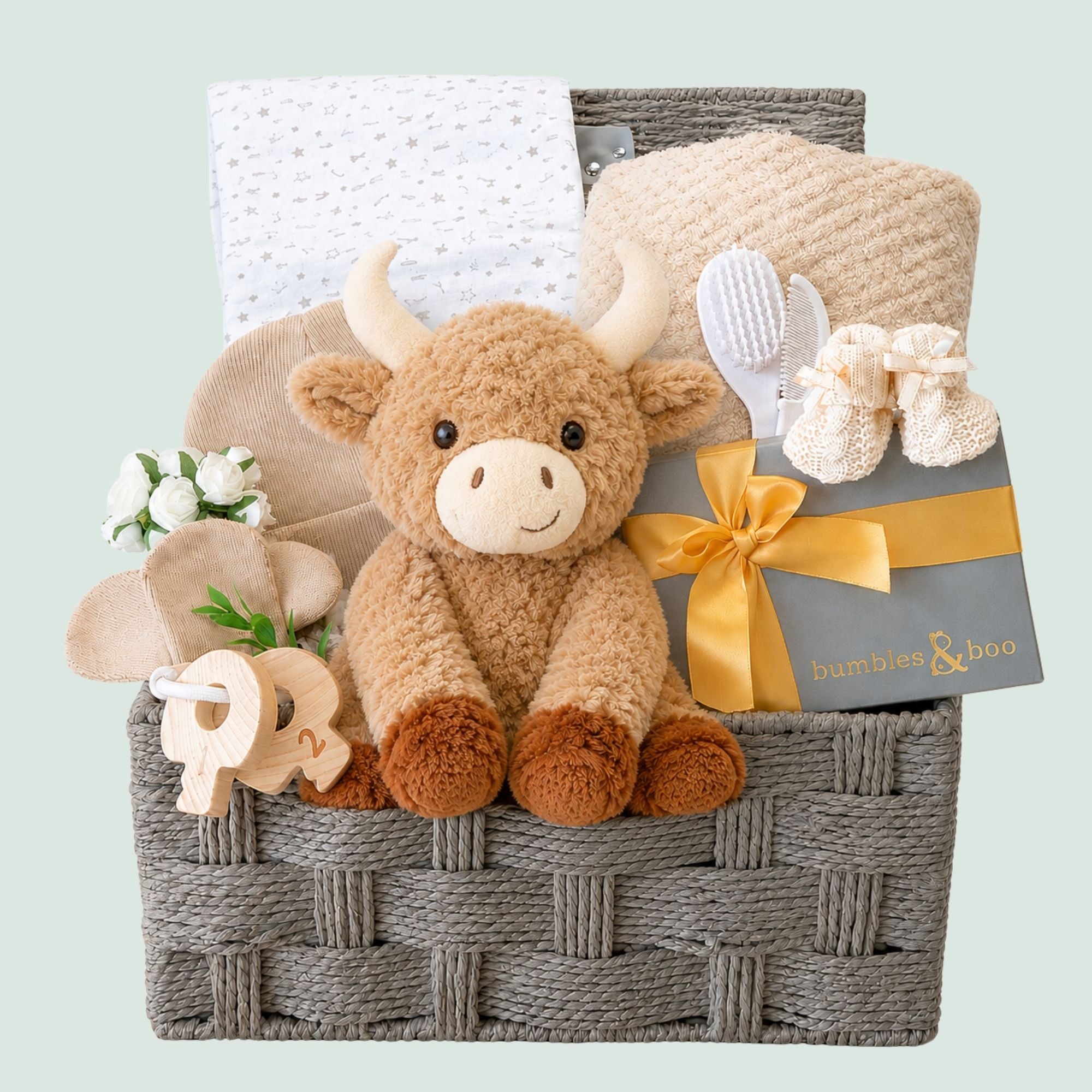 Baby shower gifts hamper with presents including plush highland cow and chocolates for the mum to be