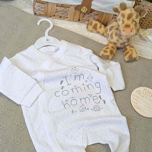 Baby sleepsuit which reads I'm Coming Home in white.