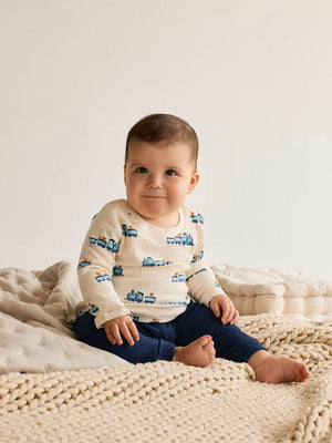 Baby wearing the white long sleeve train print T-shirt from the three pack.