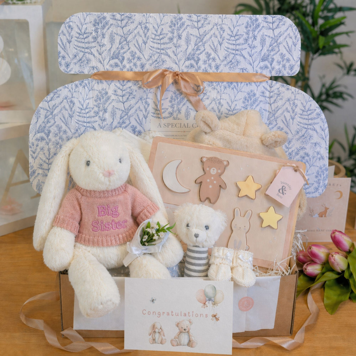 A new baby gift in a hamper box with a cuddly toy gift for the big sister.