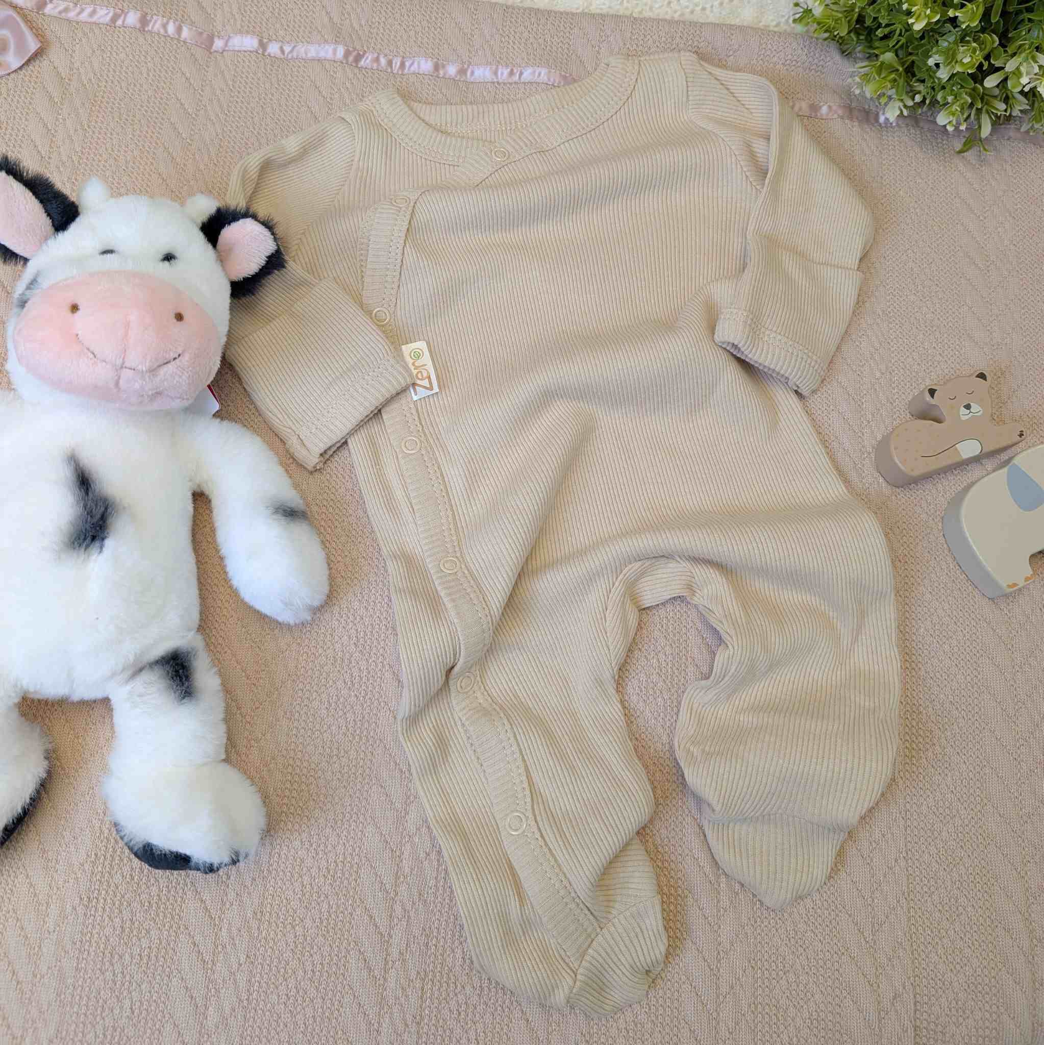Beige coloured baby sleepsuit with poppers and ribbed design.