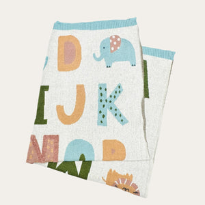 Organic cream and blue cotton baby blanket styled in a neutral nursery setting