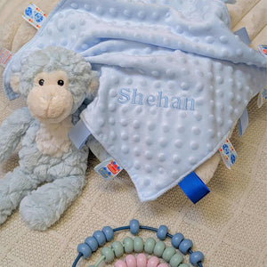 Blue baby comforter with taggie ribbons for a baby boy.