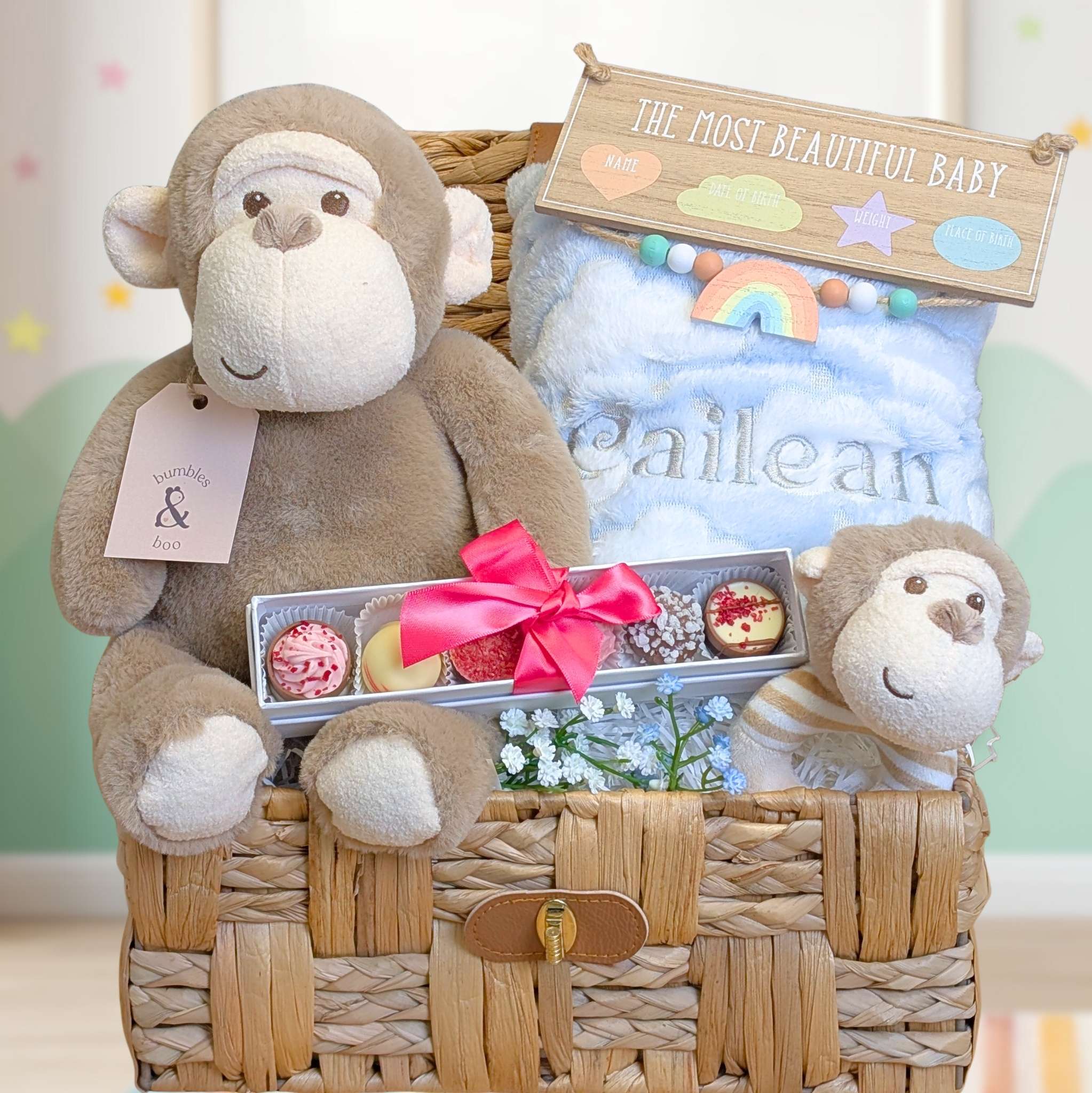 Hamper gifts basket with plush monkey toys, baby blanket and chocolates for new parents.