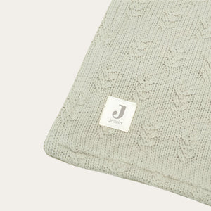 An olive green knit blanket with a fleece underside, featuring a textured grain knit pattern.
