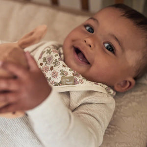 Smiling baby wearing pink and cream jersey bandana baby bib.