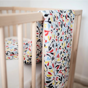 Sensory print organic cotton muslin shown in nursery hanging over cot.