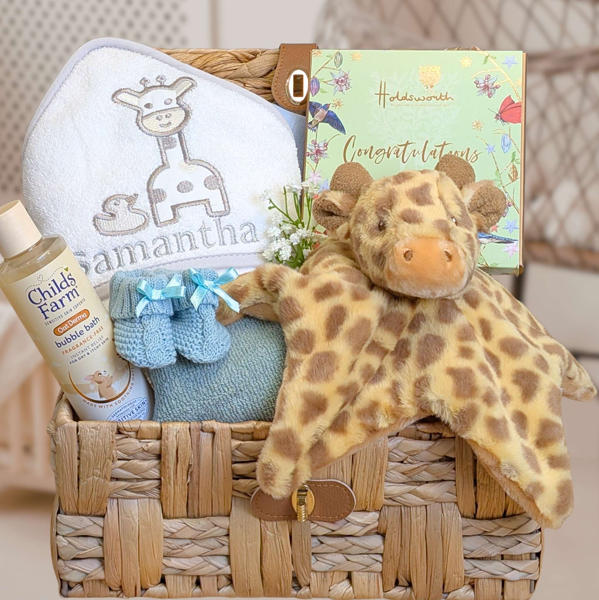 new mum gifts hamper with soft giraffe comforter and a baby bath towel in a wicker basket.
