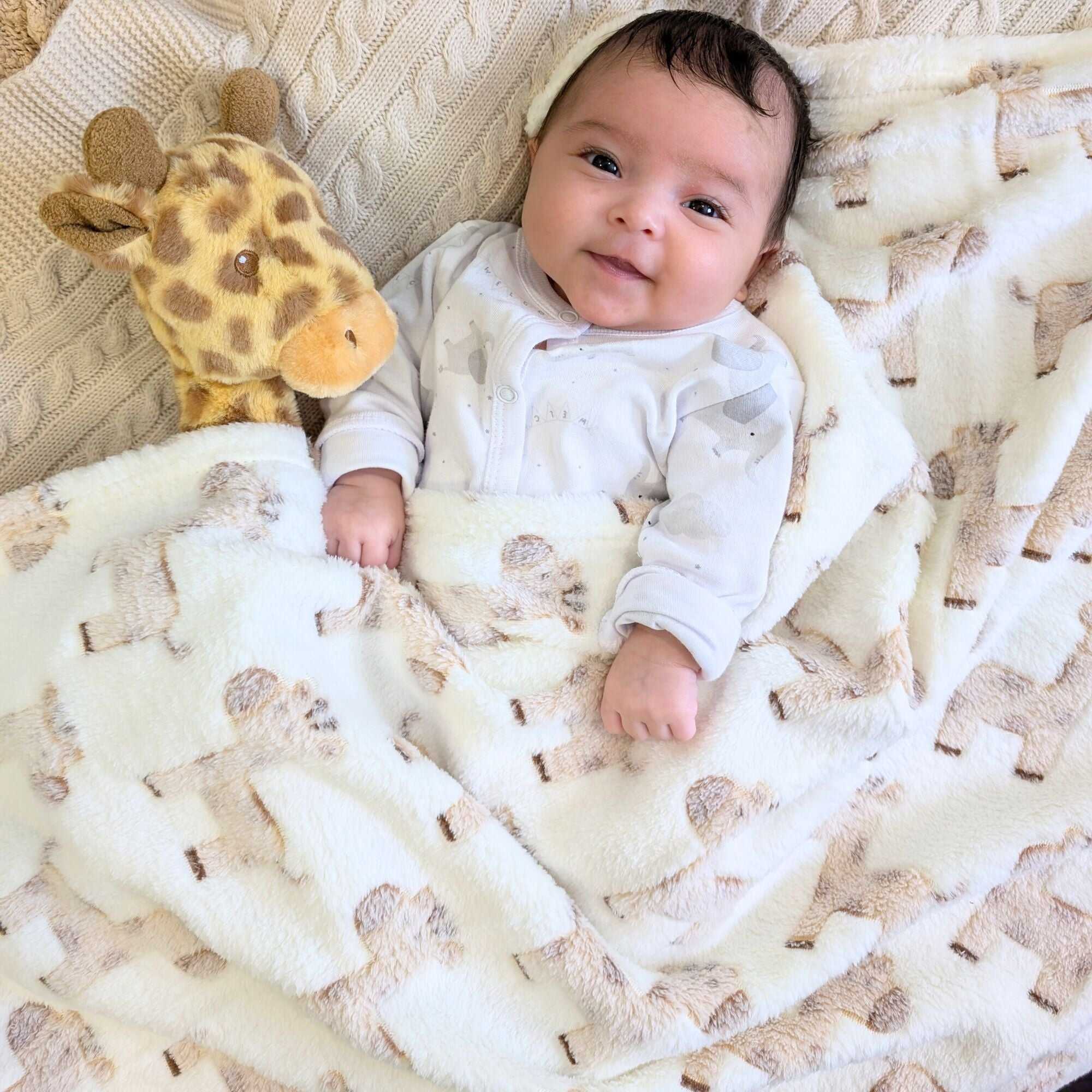 Baby blanket in cream and beige giraffe print covering a baby.