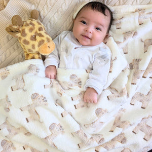 Baby blanket in cream and beige giraffe print covering a baby.