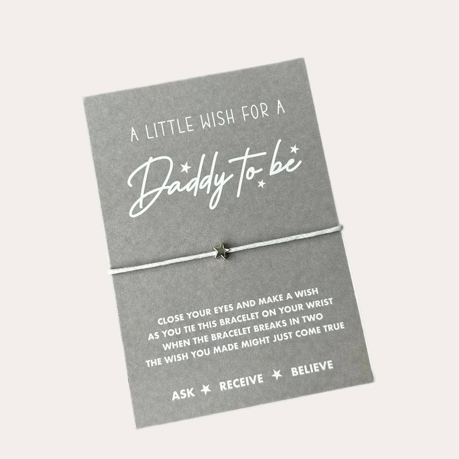 Daddy to be wish bracelet worn on the wrist with silver star charm and white cord.